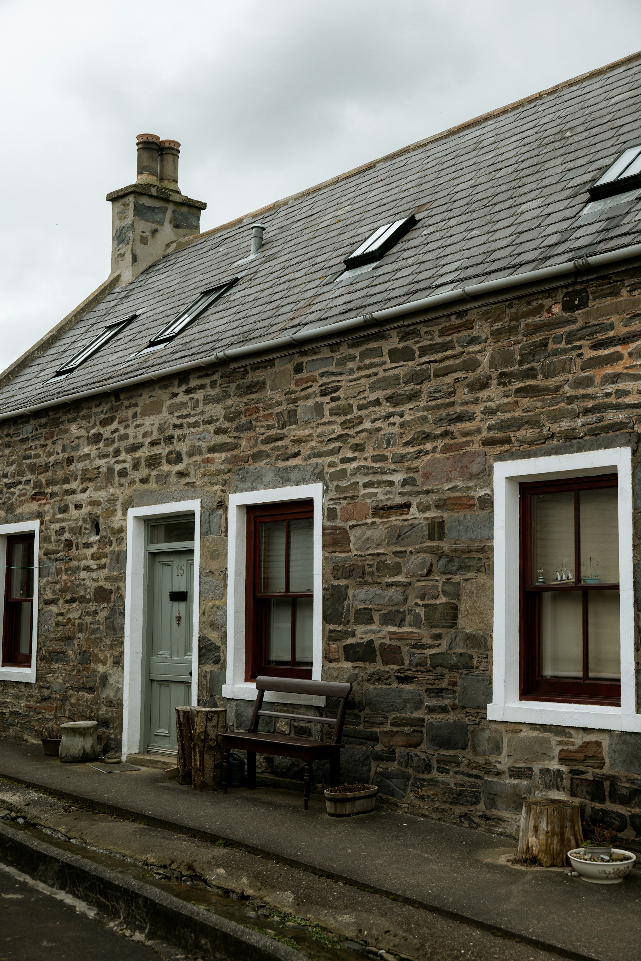 Stone house with a slate roof, roof windows and guttering.